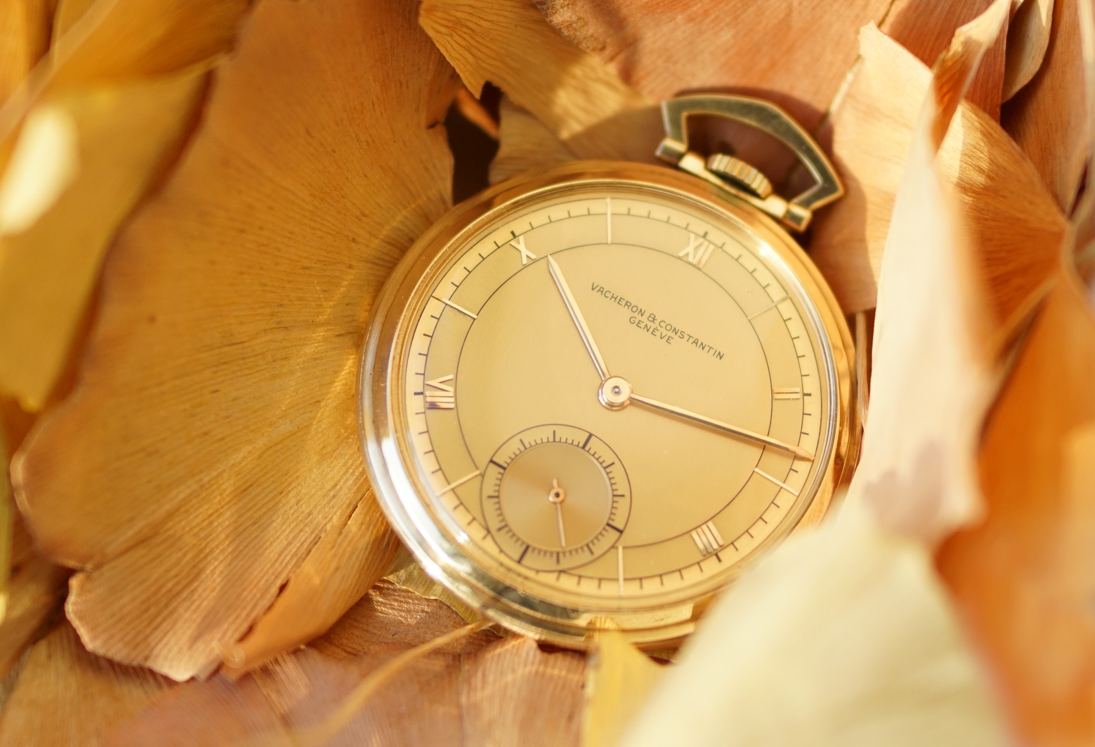 This Vacheron & Constantin pocket watch with its gold chain arranged on a pale surface