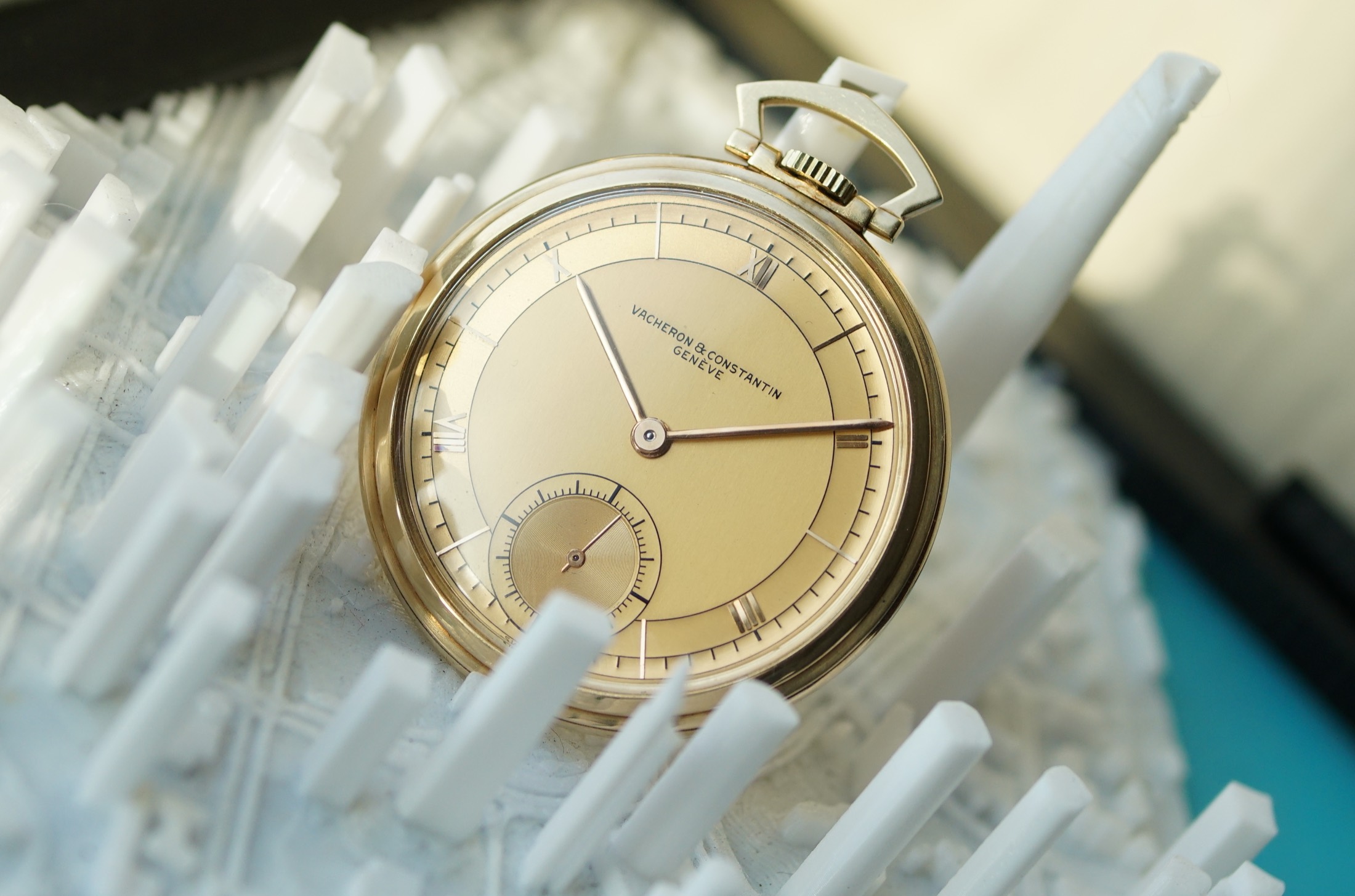 This Vacheron & Constantin pocket watch standing on wood with its gold chain
